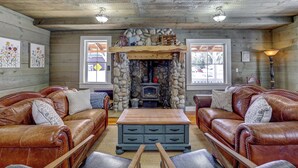 A cozy living room with a stone fireplace, leather sofas, and a wooden coffee table. - Sleeps 29!  9-bedroom 8-Bath 3-Kitchen, Historic McBride Farm in Garden Valley (Garden Valley)