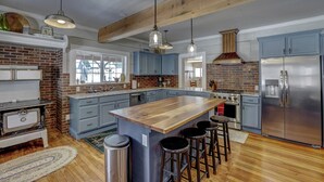 A spacious kitchen with a large island, stainless steel appliances, and blue cabinets. - Sleeps 29!  9-bedroom 8-Bath 3-Kitchen, Historic McBride Farm in Garden Valley (Garden Valley)