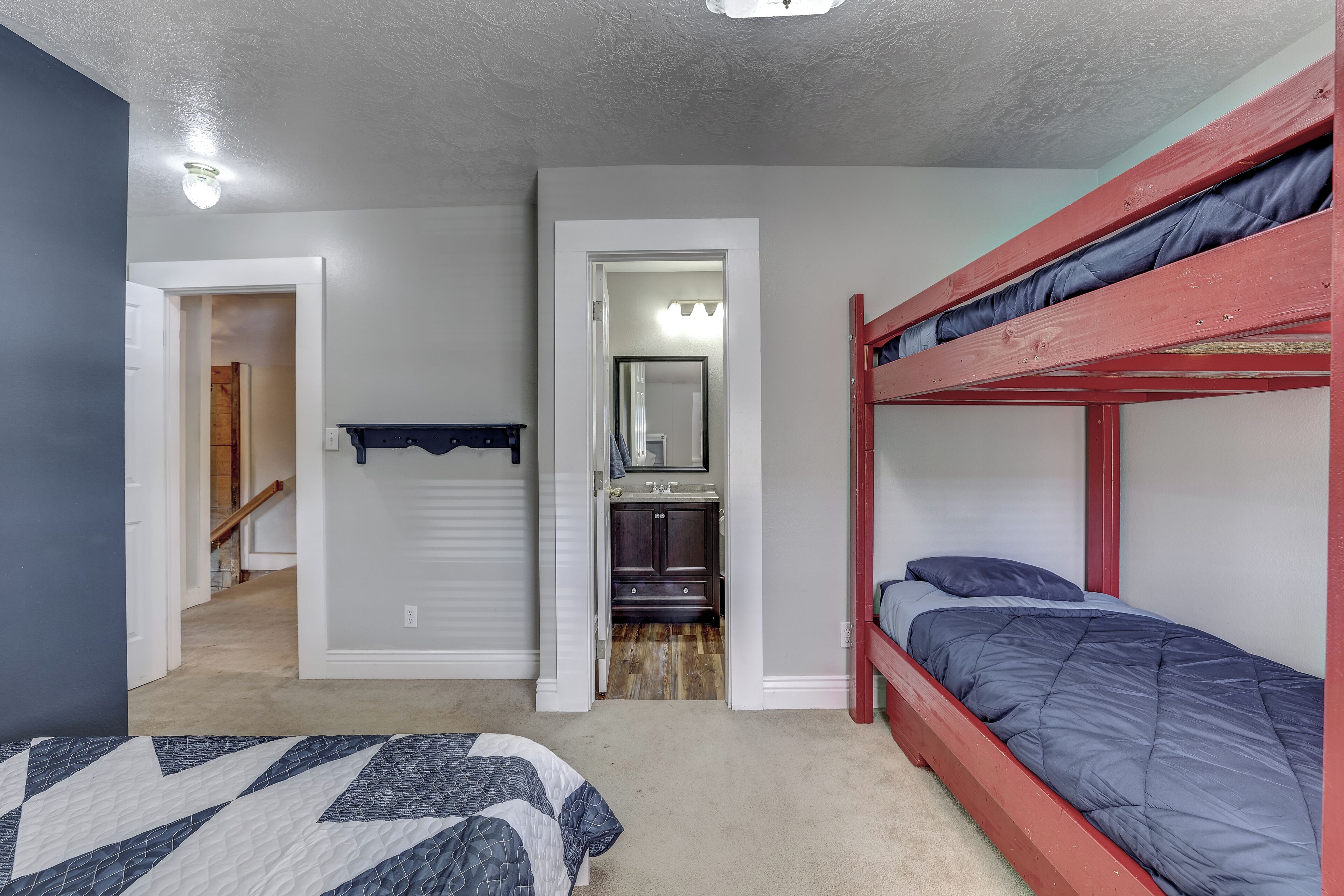 A bedroom with bunk beds, a door leading to a bathroom, and a hallway.