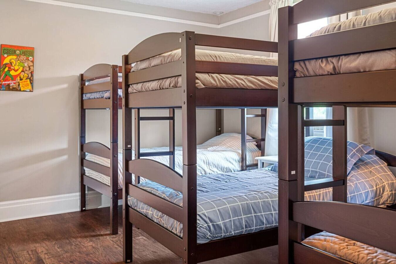 A bunk bed room with a wooden frame, a bed with a striped blanket, and a wall with a comic book.