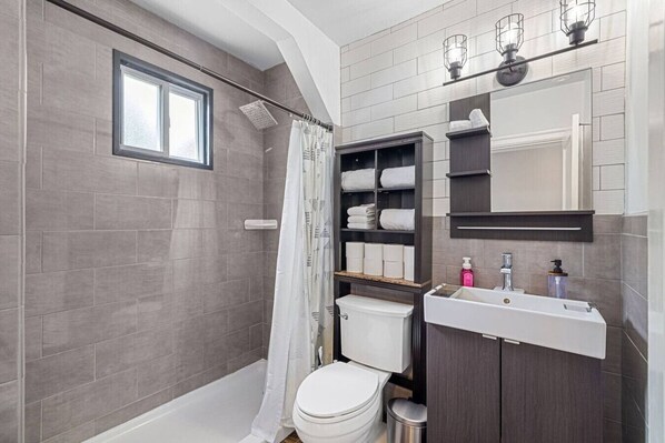A modern bathroom with a walk-in shower, a toilet, and a vanity with a mirror and sink. - Spacious 6BR Home in Mt. Washington | Private Deck |Sleeps 16 (Pittsburgh)