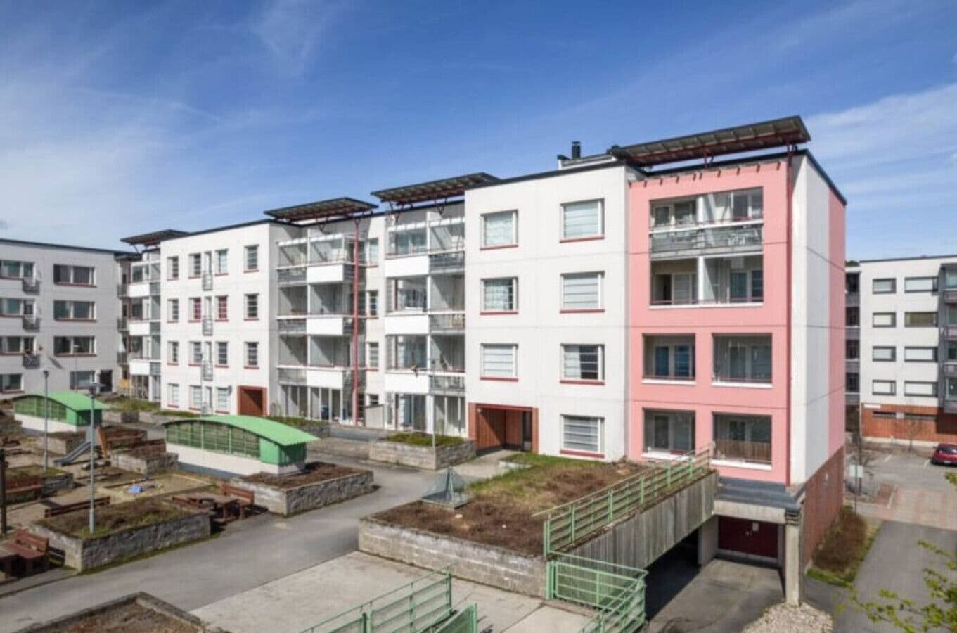 Ein mehrstöckiges Wohngebäude mit Balkonen, einem Gründach und einer Fußgängerbrücke.