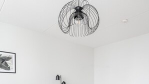 A modern living room with a grey sofa, a round coffee table, a bed, and a unique black ceiling light. - 2BR Lakefront Home near Railway Station & Downtown (Jyväskylä)