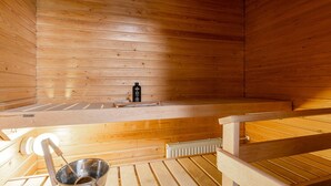A sauna with wooden walls, a bench, a metal basin, and a bottle of oil. - 2BR Lakefront Home near Railway Station & Downtown (Jyväskylä)
