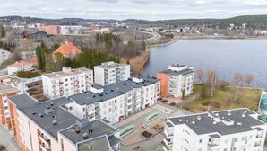 A residential area with multi-story buildings, a body of water, and a hilly landscape in the background. - 2BR Lakefront Home near Railway Station & Downtown (Jyväskylä)