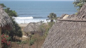 A coastal scene with thatched-roof huts, a beach, and the ocean. - 3-bedroom house in Cool Manzano Número 1 with large pool steps to the Pacific. (El Manzano Número 1)