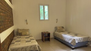 A small, clean room with two single beds, a small table, and a window. - 3-bedroom house in Cool Manzano Número 1 with large pool steps to the Pacific. (El Manzano Número 1)