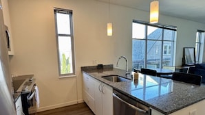 Cocina moderna con encimera de granito, electrodomésticos de acero inoxidable y un amplio ventanal que proporciona luz natural.