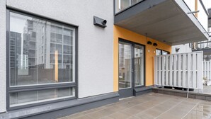 Ein modernes Gebäude mit großen Fenstern, einer gelben Akzentwand und einem überdachten Außenbereich.