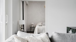 Une chambre à coucher au style minimaliste, avec un lit, des tables de chevet et une lampe.
