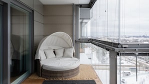 Une chambre moderne avec un lit aux lignes courbes, de grandes fenêtres et une vue sur la ville.