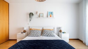 Een slaapkamer met een bed, nachtkastjes, een hangplant en wandplanken.