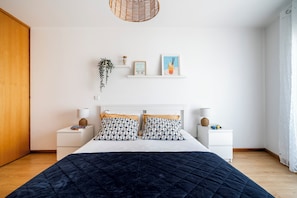 Una camera da letto con un letto, comodini, una pianta pensile e mensole a parete.