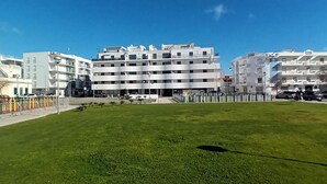 Een grasveld met moderne gebouwen op de achtergrond.