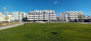 A grassy area with modern buildings in the background.
