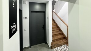 Un pasillo moderno con una puerta negra identificada con el número 301 y una escalera de madera.
