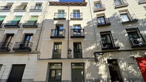 A multi-story building with balconies, a green door, and a red awning.
