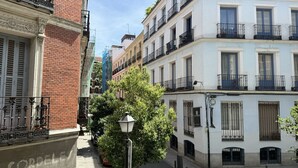 A narrow urban street with buildings featuring balconies and a street lamp.