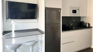 Una cocina moderna con televisión integrada, refrigerador de acero inoxidable, microondas y cafetera.