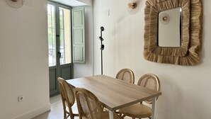 A dining area with a wooden table and wicker chairs, a rustic ceiling, and a decorative mirror on the wall.