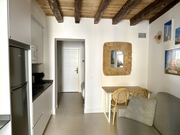 A compact kitchen with a refrigerator, microwave, and dining area with chairs and a table.