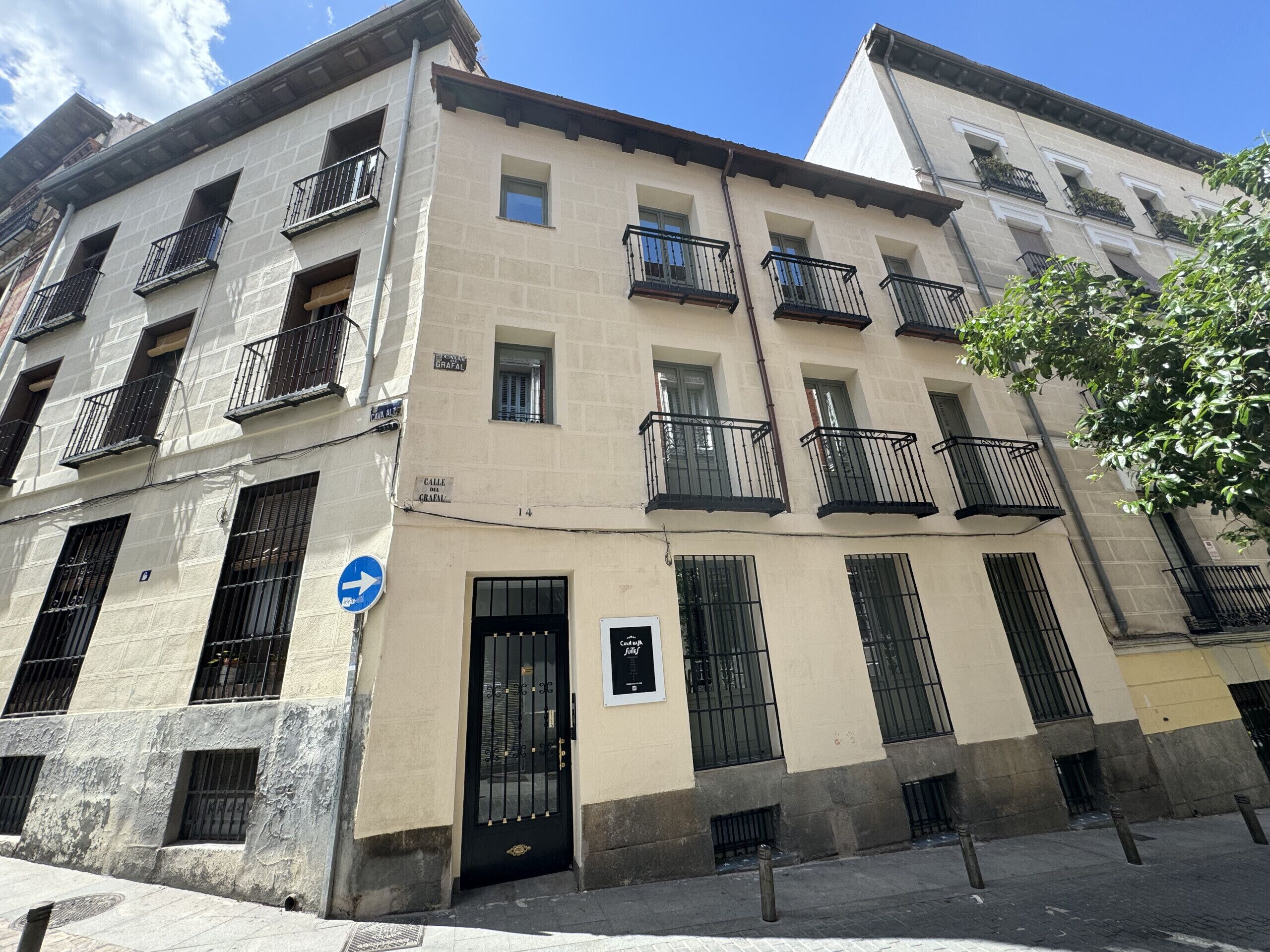 Un edificio de varios pisos con balcones, una entrada a nivel de calle y una señalización visible.
