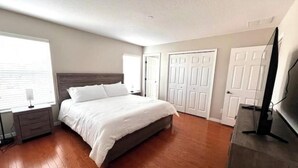 Un dormitorio con cama, mesita de noche, cómoda y televisor.
