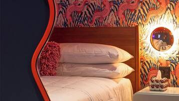Un dormitorio con una cama, una mesita de noche, un espejo y una pared decorada con un motivo de dragones.