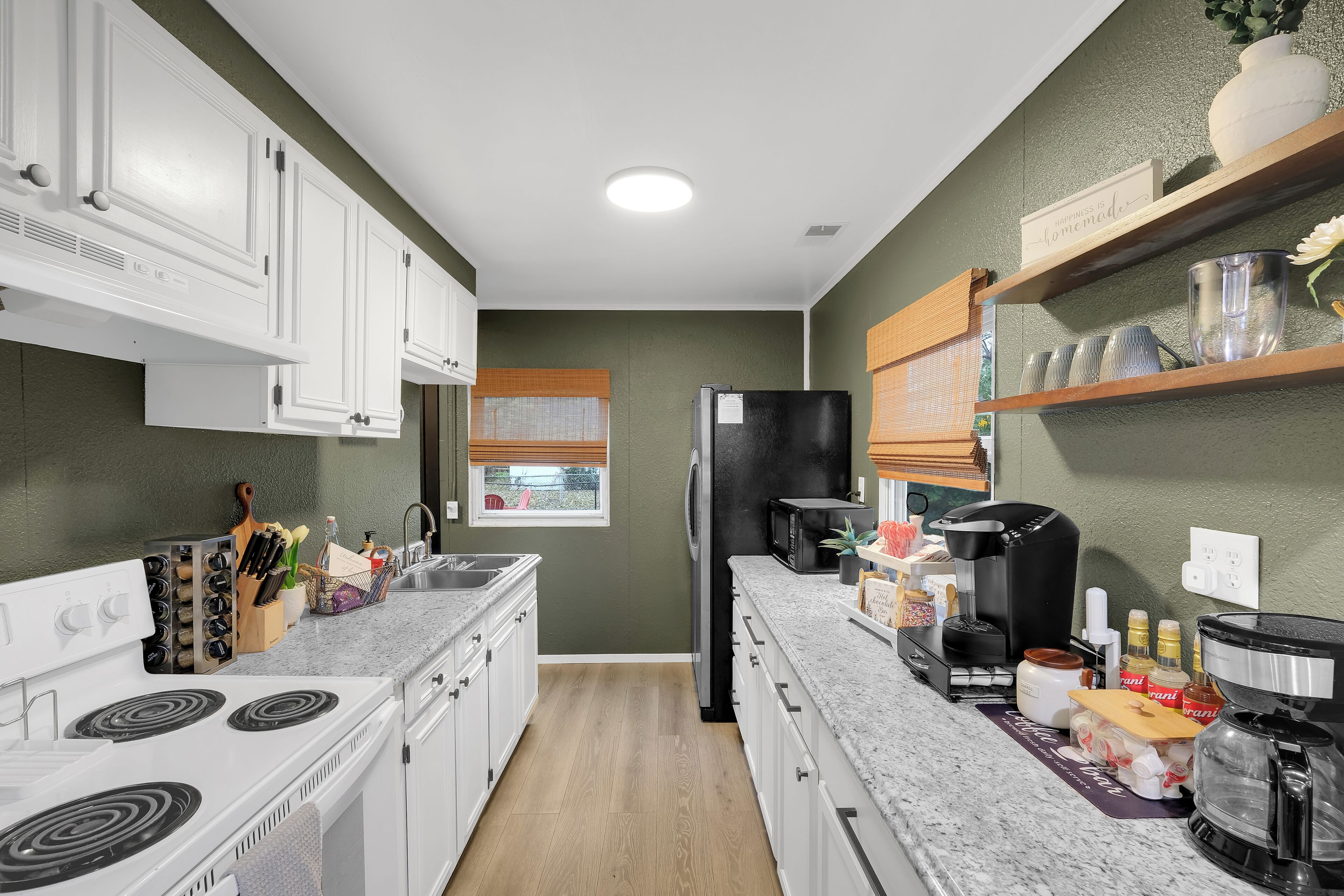 A modern kitchen with white cabinets, a black refrigerator, and a granite countertop.