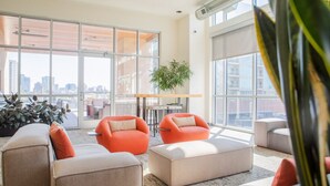 A modern lounge area with large windows, comfortable seating, and a city view.