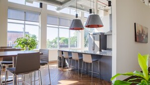 A modern kitchen with a large island, bar stools, and pendant lighting.