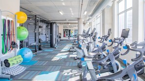 A gym with exercise equipment, a motivational quote on the wall, and large windows.
