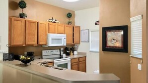 A kitchen with wooden cabinets, a white microwave, and a countertop.