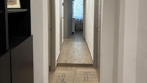 A narrow hallway with a wooden floor, white walls, and a ceiling with recessed lighting. There are two doors on either side, and a framed picture on the left wall. - A Pisa con Amore (Pisa)