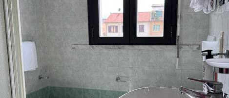 A bathroom with a bidet, a sink, and a window with blinds.