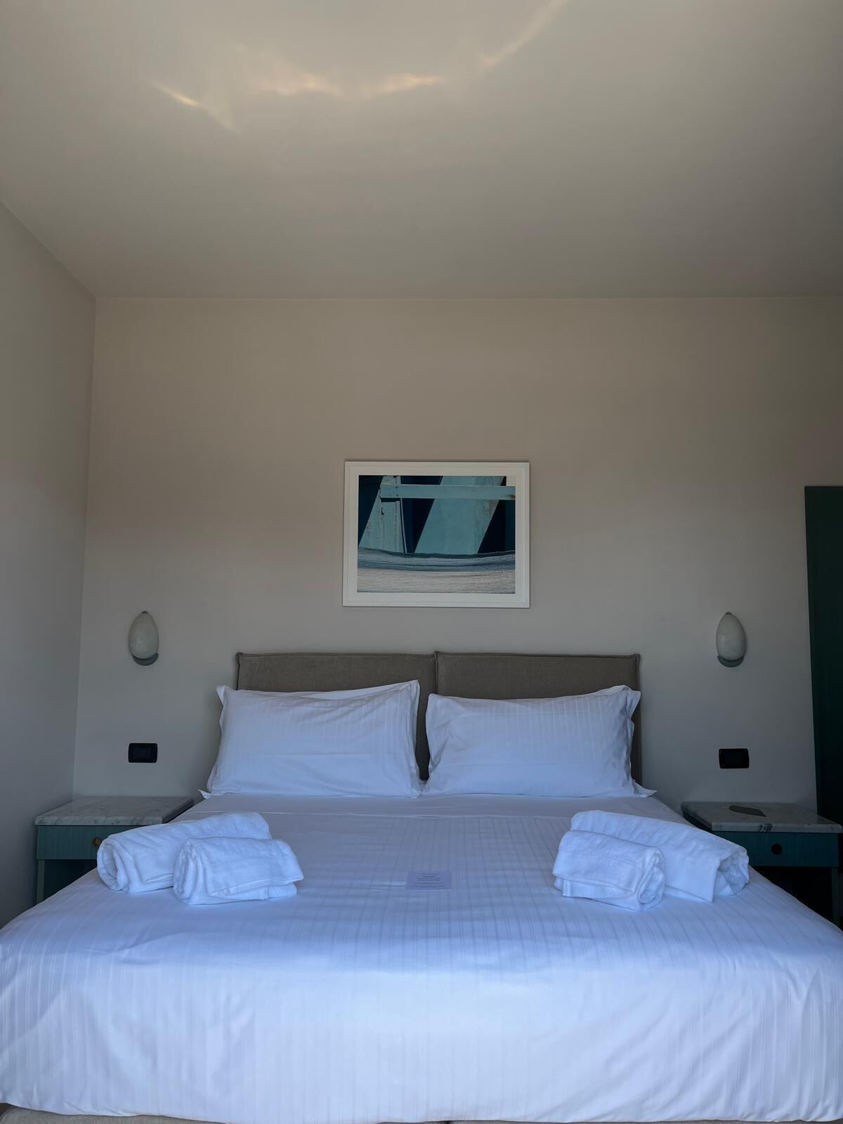 A hotel room with a large bed, two bedside tables, and a framed picture on the wall.