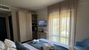 A hotel room with a bed, a TV, a wardrobe, and a window with curtains. - Hotel Harmony&Smile (Lido di Camaiore)