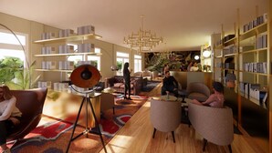 A modern library with bookshelves, a central seating area, and a unique circular light fixture. - Hotel Harmony&Smile (Lido di Camaiore)