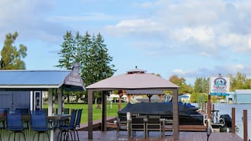 Une terrasse en bois avec des sièges extérieurs, un belvédère et une vue sur un lac.