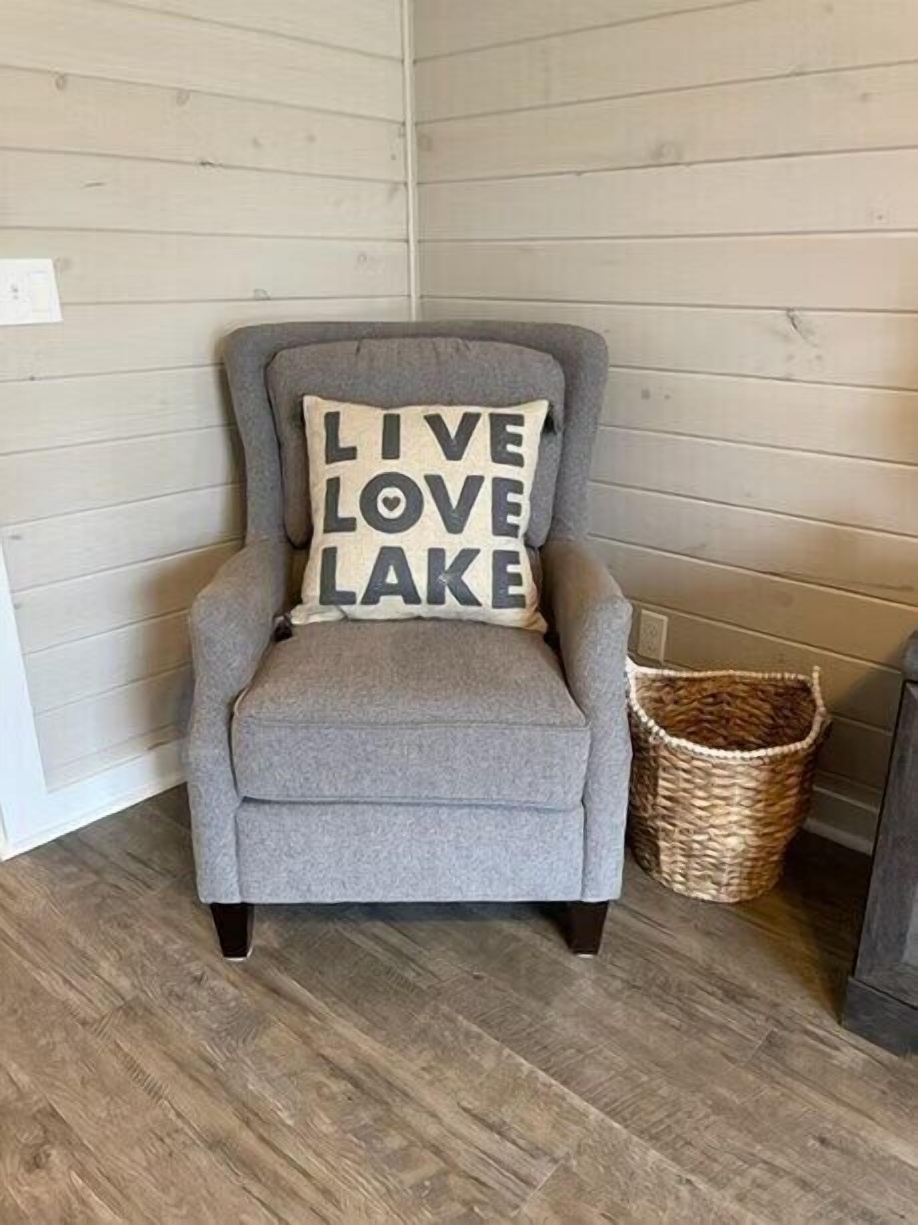 A grey armchair with a cushion that reads "LIVE LOVE LAKE."