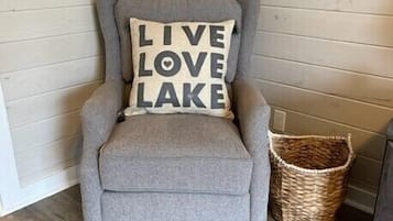 A grey armchair with a cushion that reads "LIVE LOVE LAKE."