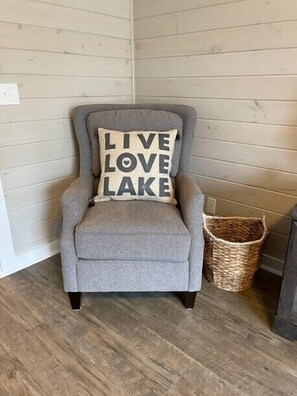A grey armchair with a cushion that reads "LIVE LOVE LAKE."