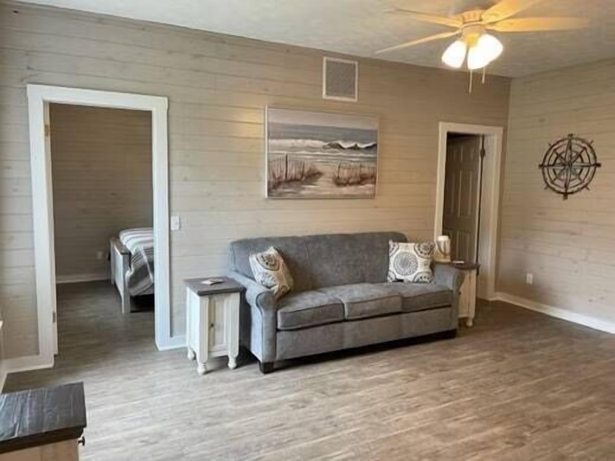 A living room with a gray sofa, a small side table, and a painting on the wall.