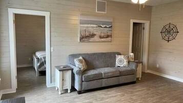 A living room with a gray sofa, a small side table, and a painting on the wall.