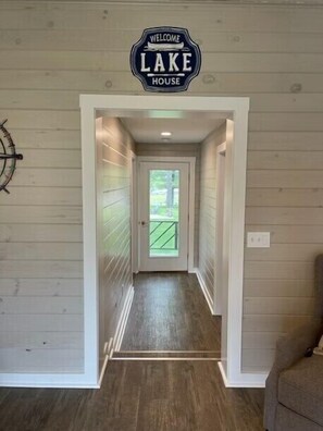 A hallway with wooden paneling, a welcome sign, and a view to the outside.