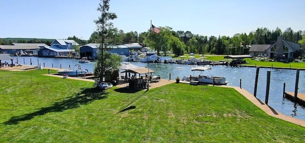 A marina with boats docked, a flagpole with an American flag, and buildings in the background.