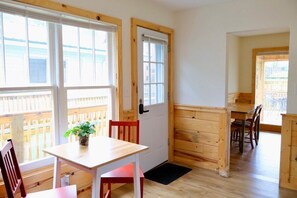 Una habitación con una mesa y sillas de madera, una planta pequeña en maceta y una puerta que da a otra estancia.