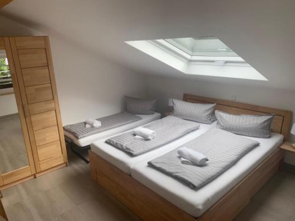 A bedroom with two beds, a skylight, and a wooden wardrobe.