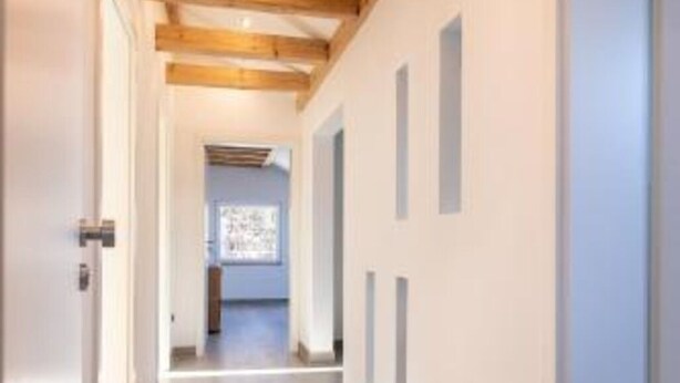 A hallway with wooden beams, white walls, and a tiled floor. - Vacation apartment *Am Bronnwiesle* (Deggingen)