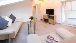A modern living room with a sofa, a glass coffee table, and a TV stand. - Vacation apartment *Am Bronnwiesle* (Deggingen)